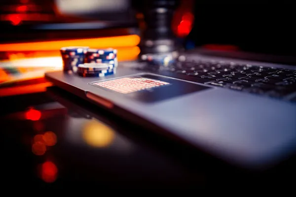 A woman smiling while playing online games on her laptop, surrounded by neon casino elements, showcasing JLWILD’s diverse game collection.